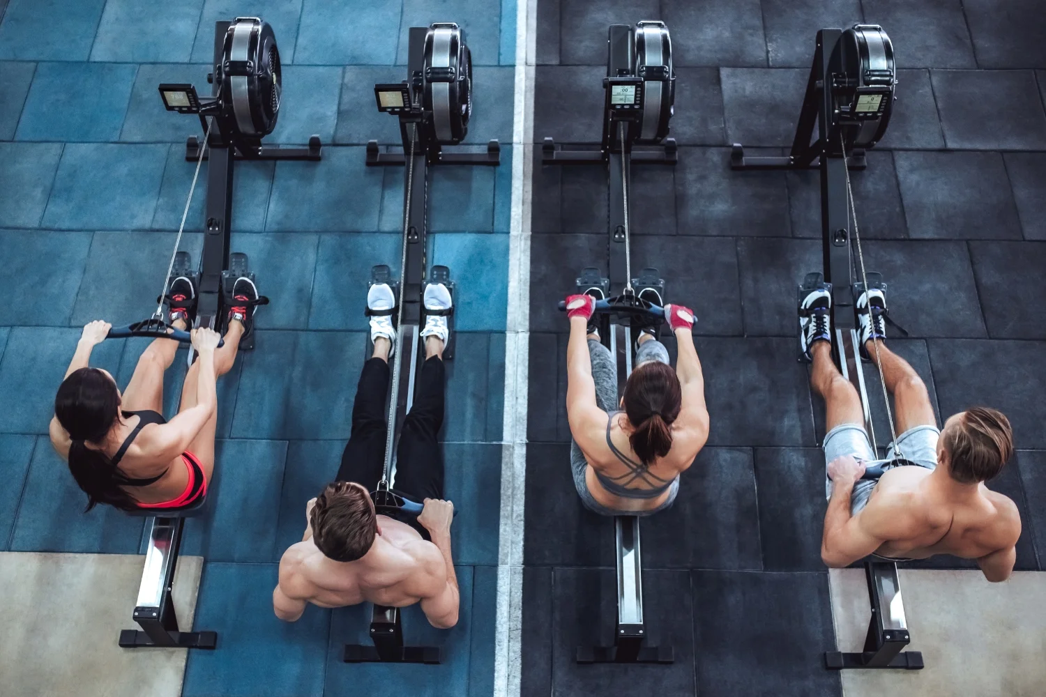 Four gym-goers using rowing machines in a fitness studio, focusing on exercise and training, showcasing a modern gym environment.