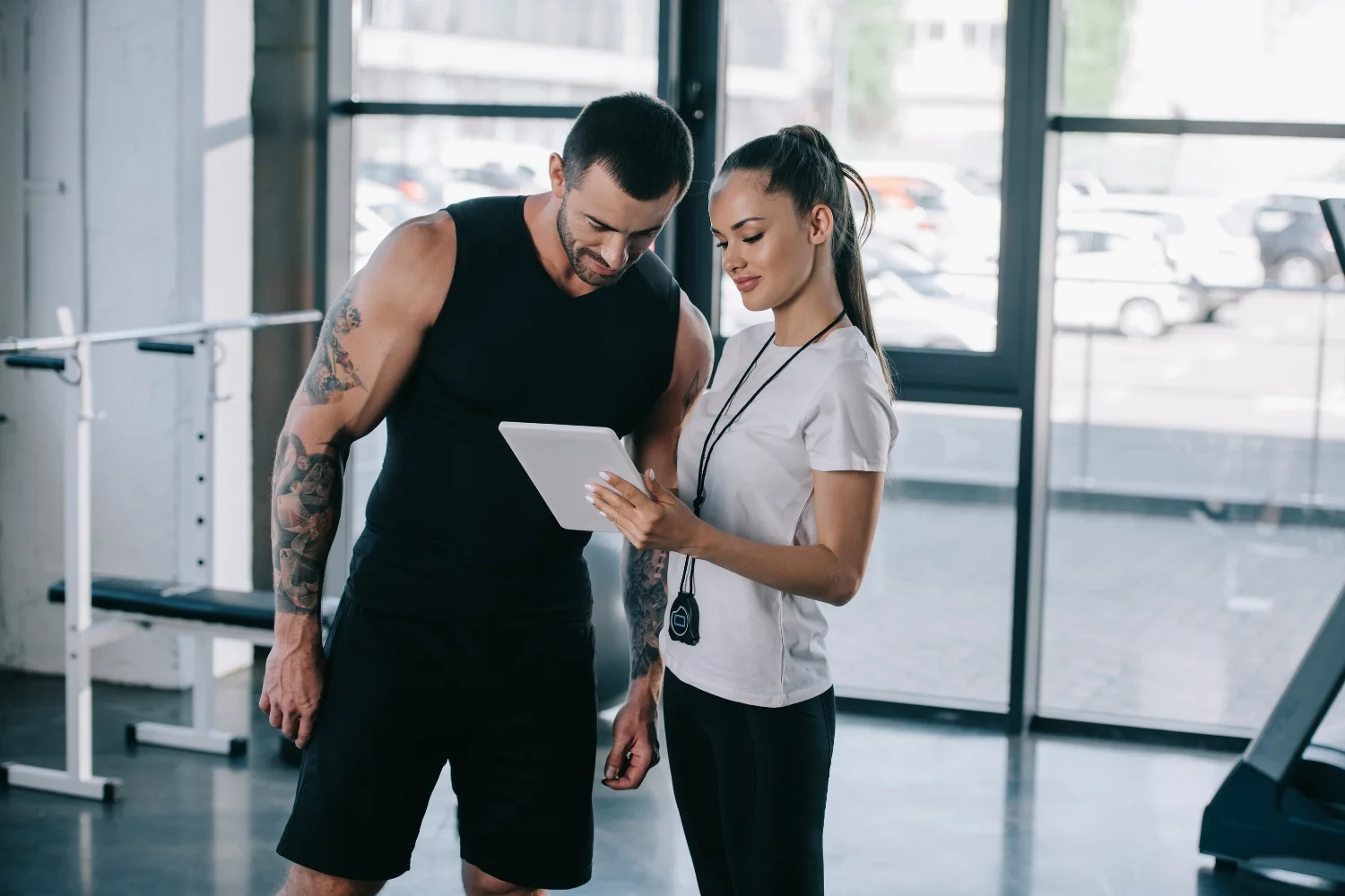 Man and woman discussing fitness plans on tablet in gym setting, highlighting gym marketing and member engagement strategies.